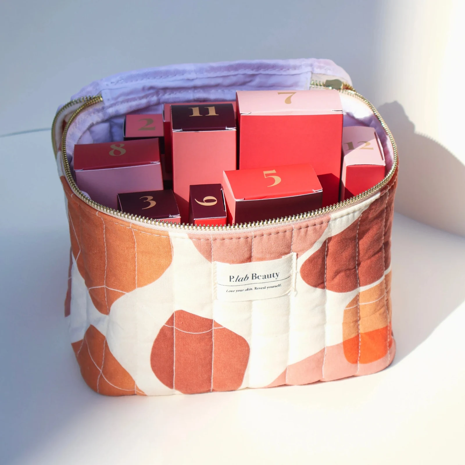 Vanity P.Lab Beauty à motifs orangés, ouvert sur des boîtes roses et rouges numérotées.