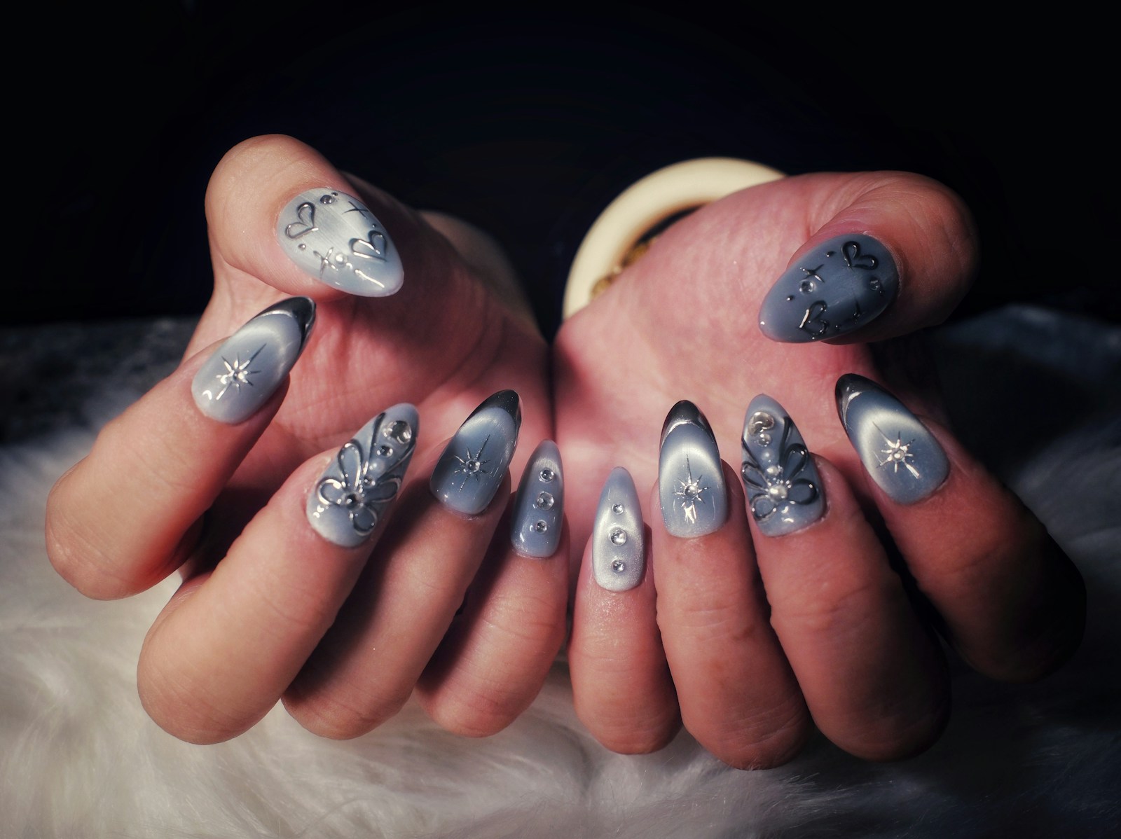Manucure argentée aux reflets lumineux, avec décorations sur des ongles longs.